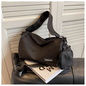 Detail of black nylon shoulder bag featuring fashion patch and removable small pouch