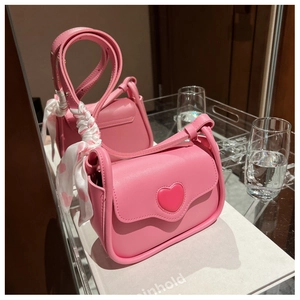 Detail of pink heart-shaped crossbody bag featuring a decorative red heart silk scarf