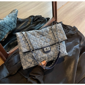 Detail of blue denim quilted handbag with silver chain and metal twist lock