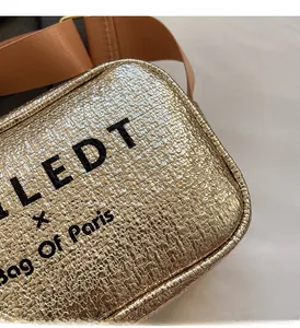Macro detail of gold metallic crossbody bag with LEDT logo and wide orange strap