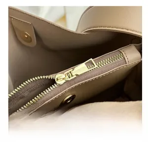 Detail view of smooth zipper closure and magnetic buckle on beige large capacity bucket bag