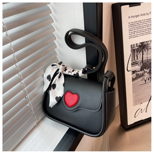 Detail of black leather crossbody bag with a 3D red heart and decorative heart silk scarf