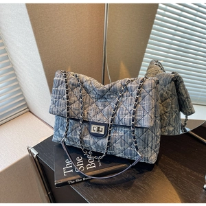 Detail of blue denim quilted chain bag with silver twist lock on vintage books