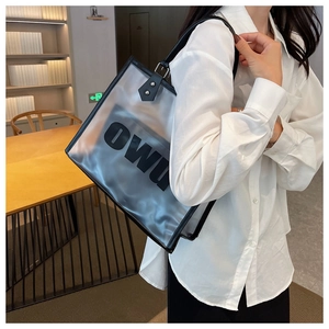 Detalle del bolso tote negro esmerilado translúcido con letras OW y correa de cuero