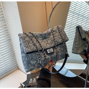 Detailed view of blue denim quilted chain bag with silver twist lock and metal strap