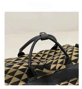 Détails du sac de voyage en toile montrant le motif jacquard et l'anse en cuir