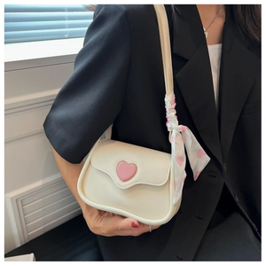 Close-up of small creamy white crossbody bag with a pink 3D heart and floral silk scarf