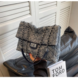 Detail of blue quilted tweed shoulder bag with silver turn-lock and chain strap