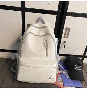 Detail of a cream-white nylon backpack featuring multiple pockets and buckle straps