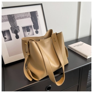 Minimalist beige leather tote bag displayed in a modern urban interior setting
