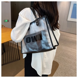 Detalle de bolso tote de PVC transparente con neceser negro y logotipo OWU