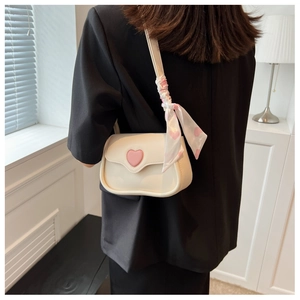 Detail of a mini cream crossbody bag with 3D pink hearts and silk scarf on the shoulder strap