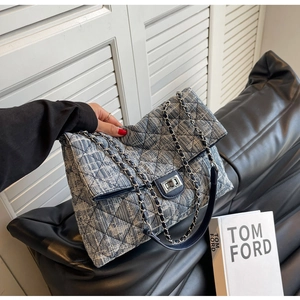 Detail of blue and white tweed texture with quilted rhombic pattern and silver chain strap