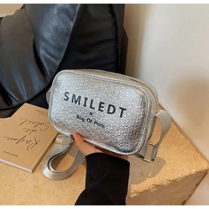 Detail of silver textured crossbody bag with wide shoulder strap on stone surface