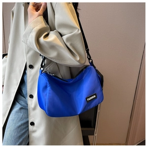 Detail of royal blue nylon crossbody bag with adjustable strap and fashion label detail