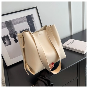 Detail of minimalist cream bucket bag showing high-quality leather texture and gold hardware