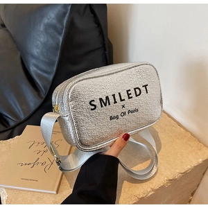 Detail of silver textured crossbody bag with wide strap and metallic brand logo