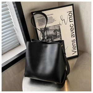 Detail view of a black matte leather bucket bag showing its sleek texture and shoulder strap