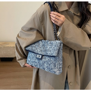 Detail of blue quilted tweed shoulder bag with silver turn-lock and chain strap on a model