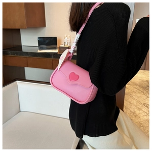 Detail of pink PU leather crossbody bag with heart logo and silk scarf woven strap