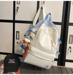 Detailed view of tricolor campus backpack featuring light blue straps and a cow plush charm