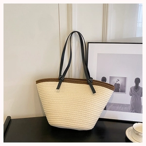 Detail of woven tote bag featuring a brown trimmed edge and slim black leather handles