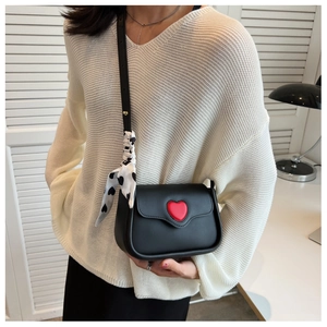 Detail of black crossbody bag featuring a red heart and silk scarf wrapped handle