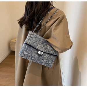 Detail of tweed quilted crossbody bag with silver twist lock and woven chain strap
