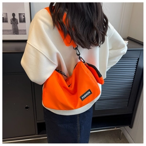 Close-up of bright orange nylon crossbody bag with fashion label and small detachable pouch