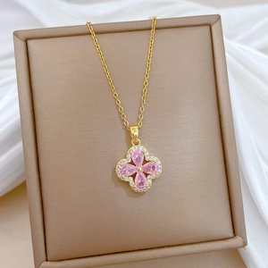Macro view of four-leaf flower pendant with pink pear-shaped gemstones and gold chain