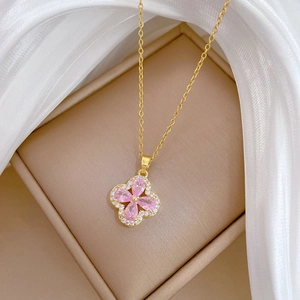 Macro detail of pink zircon clover pendant with gold titanium steel chain and silk background