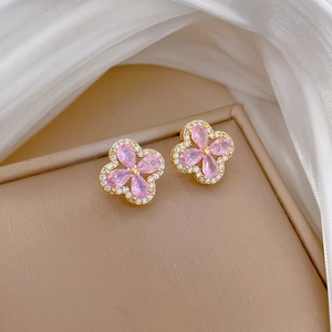 Close-up of gold-plated clover earrings featuring pink teardrop stones and pavé zircon