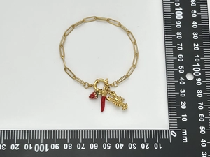 Detail of gold-plated chain bracelet with strawberry, chili and lobster charms