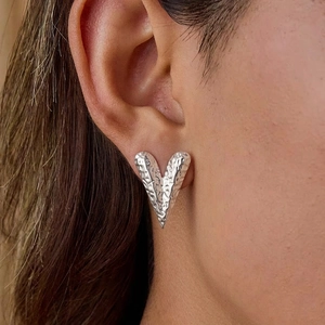 Silver hammered heart earrings in 18K gold plated stainless steel on model ear
