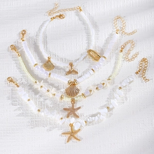 Primer plano de conjunto de tobilleras de cuentas blancas con estrellas de mar y caracolas.