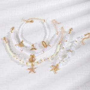 Detalle de juego de tobilleras con dijes de estrella de mar y concha para vacaciones.