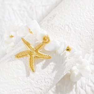 Primer plano de tobillera de estrella de mar dorada con cuentas blancas para la playa.