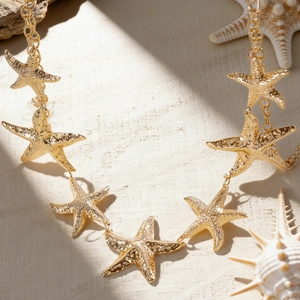 Nahaufnahme einer goldenen Seestern-Taillenkette mit strukturierten Ozean-Details.