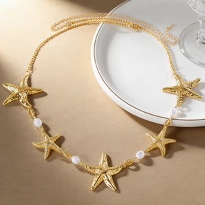 Elegante goldene Seestern-Taillenkette mit weißen Perlen auf einem weißen Keramikteller