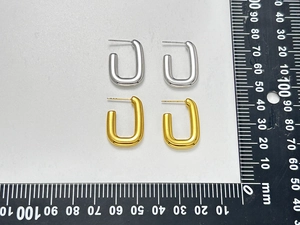 Minimalist geometric U-shaped gold and silver earrings shown with millimeter scale