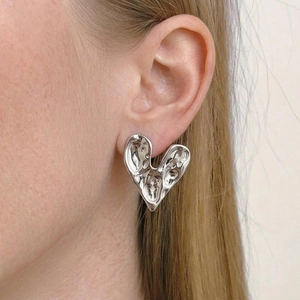 Boucles d'oreilles cœur dorées 18K style vintage avec texture de lave sur modèle