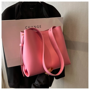 Detail of a pink leather tote bag with wide shoulder strap and modern side ties