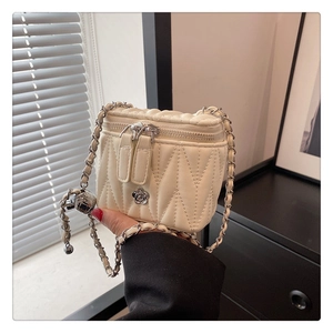Detail der cremefarbenen Stepptasche mit silberner Kamelien-Verzierung und Kettenriemen