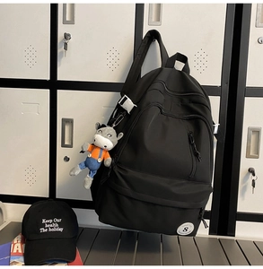 Detail of black multi-zipper backpack with white buckles and donkey plush pendant
