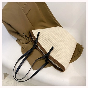 Detail of large woven tote bag in cream white with brown trim and slim black straps