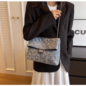 Close-up of blue and white tweed crossbody bag with quilted pattern and chain strap