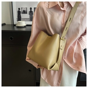 Detail of khaki leather bucket bag with adjustable wide shoulder strap on casual outfit
