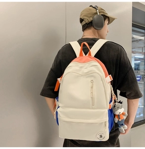 Male model wearing the beige large capacity backpack with orange handles and plush donkey charm