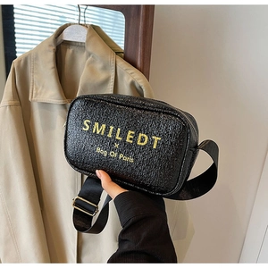 Close-up of black crossbody bag with pleated texture and yellow SMILEDT lettering