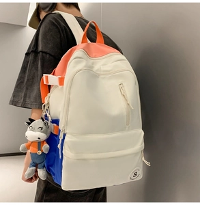 Detail of color-block backpack with adjustable straps and cute plush pendant charm